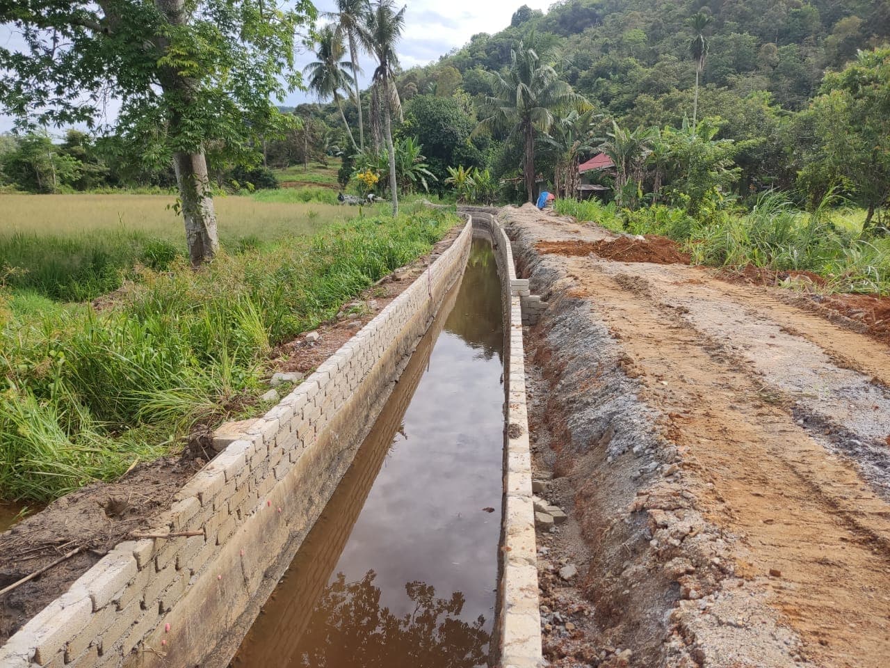 Parit konkrit yang siap dibina di tepi sawah dan jalan ladang